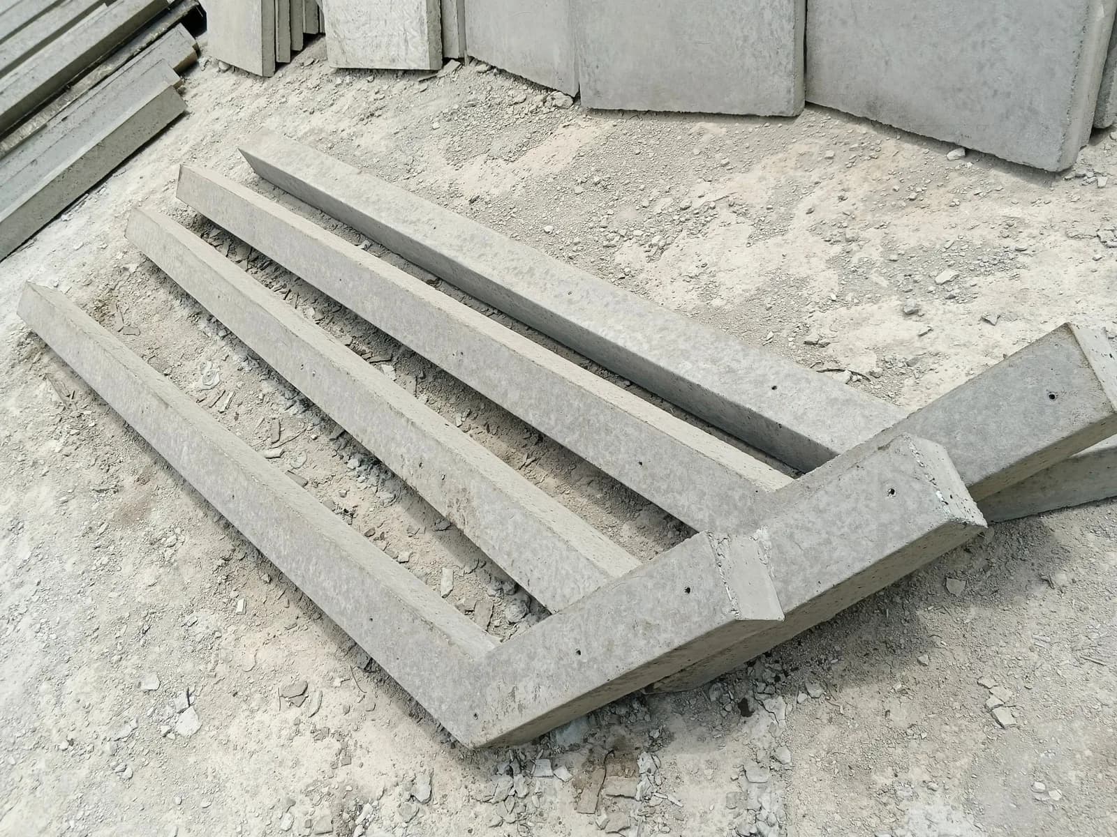 Reinforced concrete fencing poles with cranked tops stacked at the yard