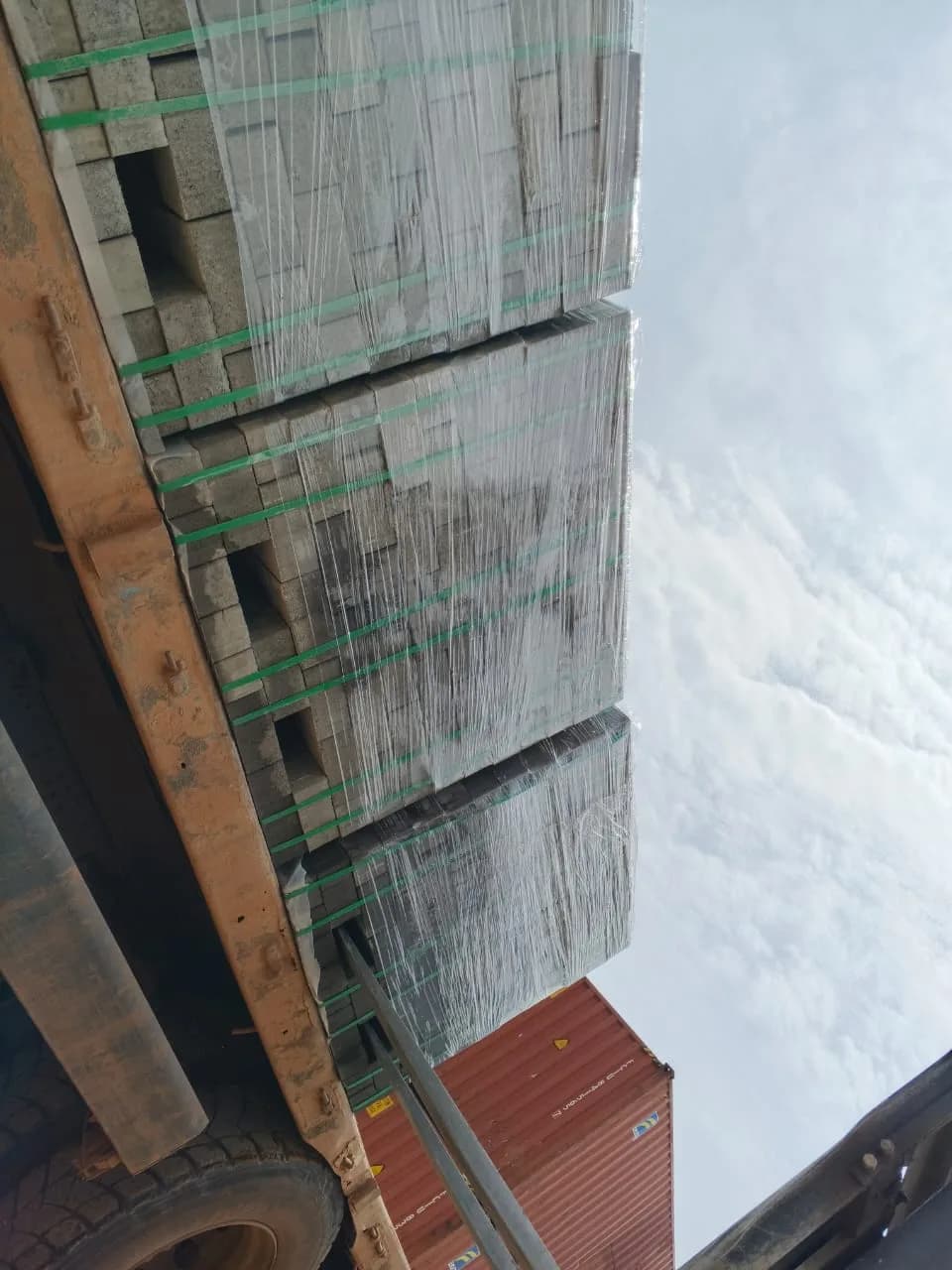 Flatbed truck loaded with wrapped pallets of pavers